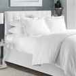 Pictured: Modern bedroom setting with a nicely made white bed in the center. The bed sits on top of a white fabric bedframe. The bedding featured is the Naked T-300 Duvet Cover and the Naked T-300 Sheets.