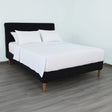 Pictured: Nicely made white bedding on a black fabric bedframe. The bed features the white Martex Suites Coverlet, which has a luxurious herringbone pattern.