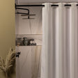 White shower curtain in a bathroom with marble walls and decorative elements.