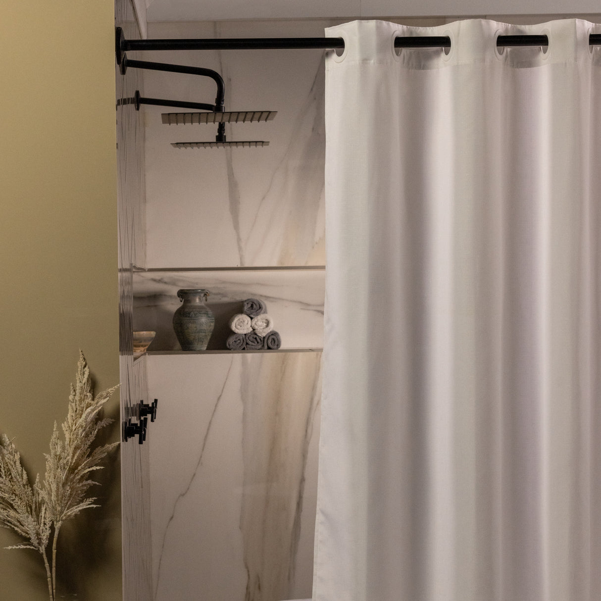White shower curtain in a bathroom with marble walls and decorative elements.