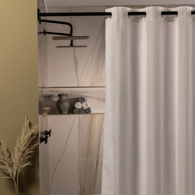 White shower curtain in a bathroom with marble walls and decorative elements.