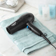 Black hair dryer on a light blue towel with a white background