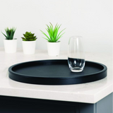 Black tray on a white surface with a glass and small plants.