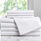 Pictured: Neatly folded stack of white sheets on a marble countertop in front of a window. The product featured are the Millennium T-300 Sheets.