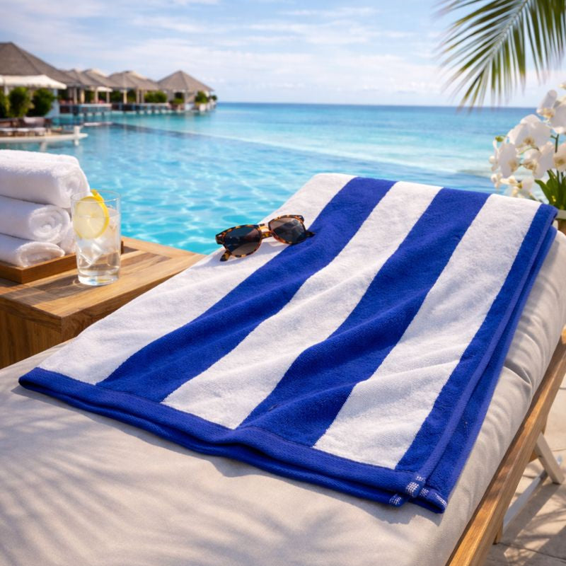 Blue and white striped towel on a sunbed by a pool with ocean view