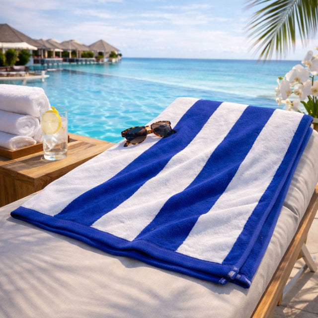 Blue and white striped towel on a sunbed by a pool with ocean view