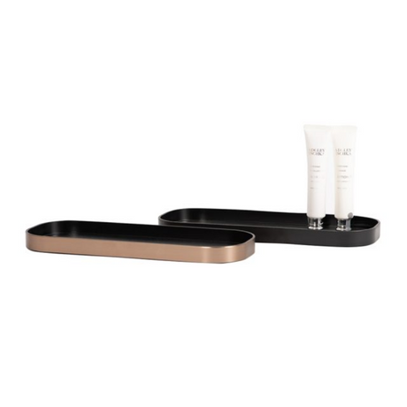 Two black trays on a white background with a white bottle on one tray.