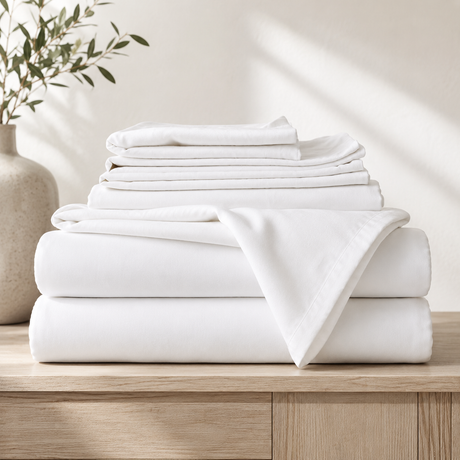 Stack of white folded sheets on a wooden surface with a neutral background