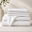 Stack of white folded sheets on a neutral background