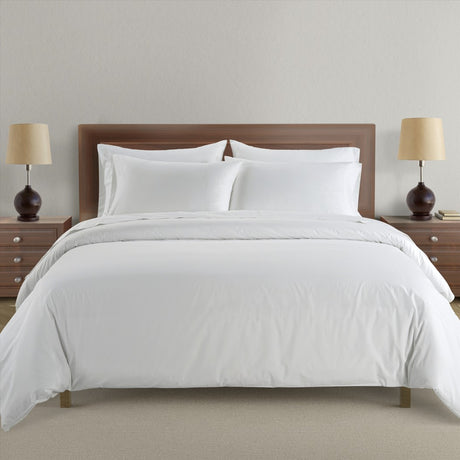 White bedding set on a bed with wooden headboard and nightstands with lamps.