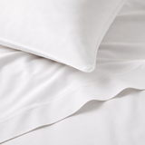 Close-up of white bedding with a pillow on a light gray background