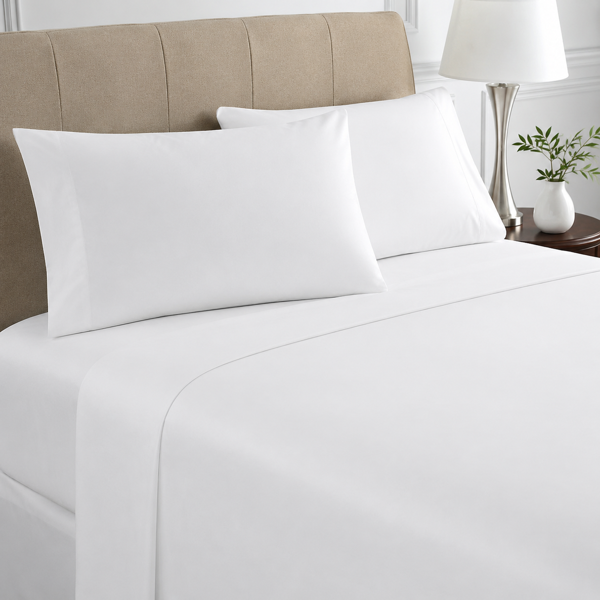 White bed sheets and pillows on a neatly made bed with a beige headboard.