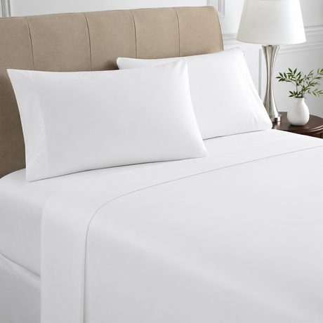 White bed sheets and pillows on a neatly made bed with a beige headboard.