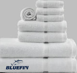 Product showcases variety of towels from the Bluefin collection by Boston Textile Co. Products are neatly rolled in order of size from wash cloths to hand towels to bath towels.