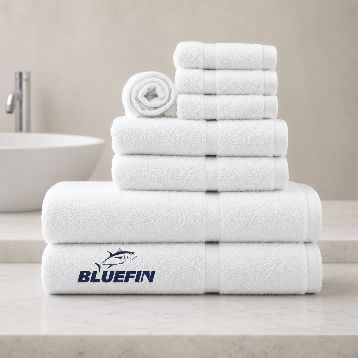 Stack of white towels with Bluefin logo on a bathroom counter