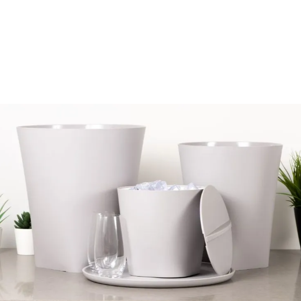 Set of white trash bins with a lid on a light surface, with plants in the background.