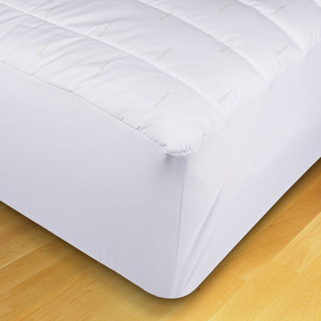 Pictured: Shot of the corner of the white EcoPure Mattress Pad against light wood flooring. You can see the the Eco Pure logo repeated pattern on the top of the mattress.