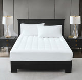 A white, plush mattress topper on a bed with two pillows, in a room with nightstands and lamps on either side of the bed.