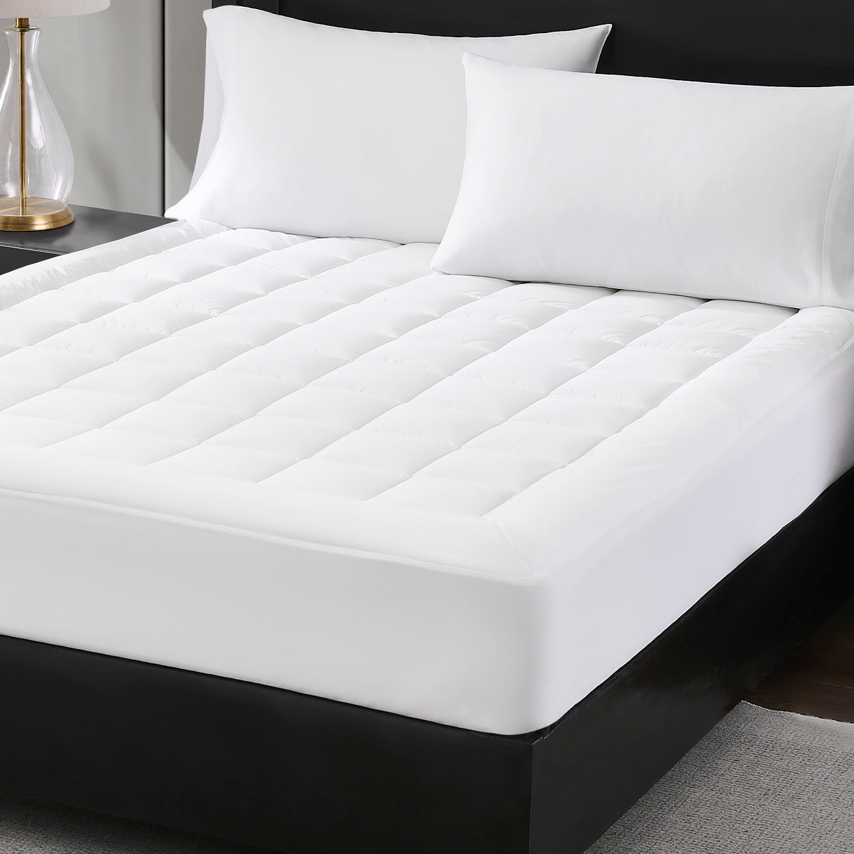 White mattress pad on a bed with pillows in a bedroom setting