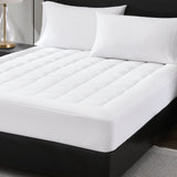White mattress pad on a bed with pillows in a bedroom setting