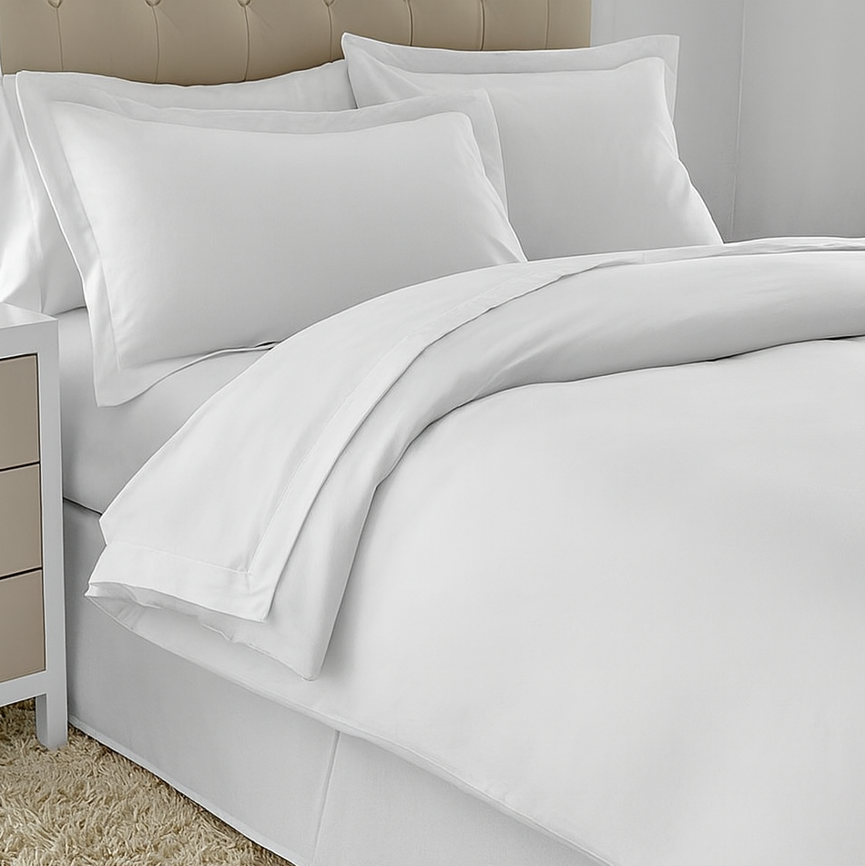 White bedding set on a bed with beige headboard and carpet.