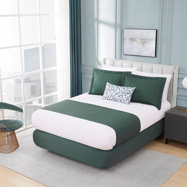 Modern bedroom with a green and white bed, side table, and chair.