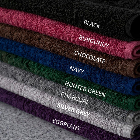 Stack of folded towels in various colors with labels on a textured surface