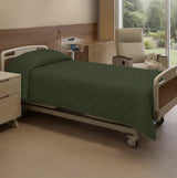 Hospital bed with green bedding in a room with a window view