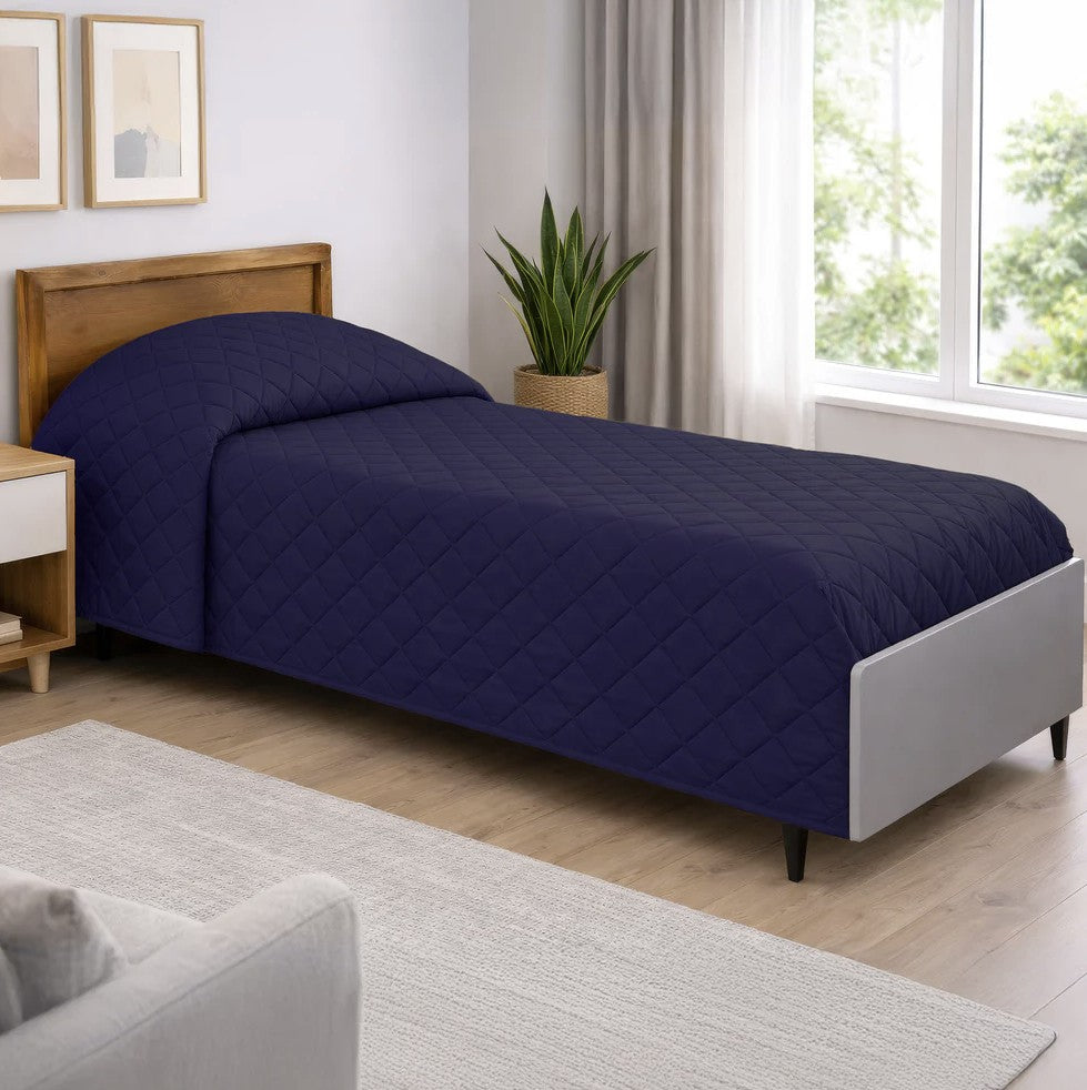 Bedroom with a bed covered in a navy quilt, wooden headboard, and light decor.