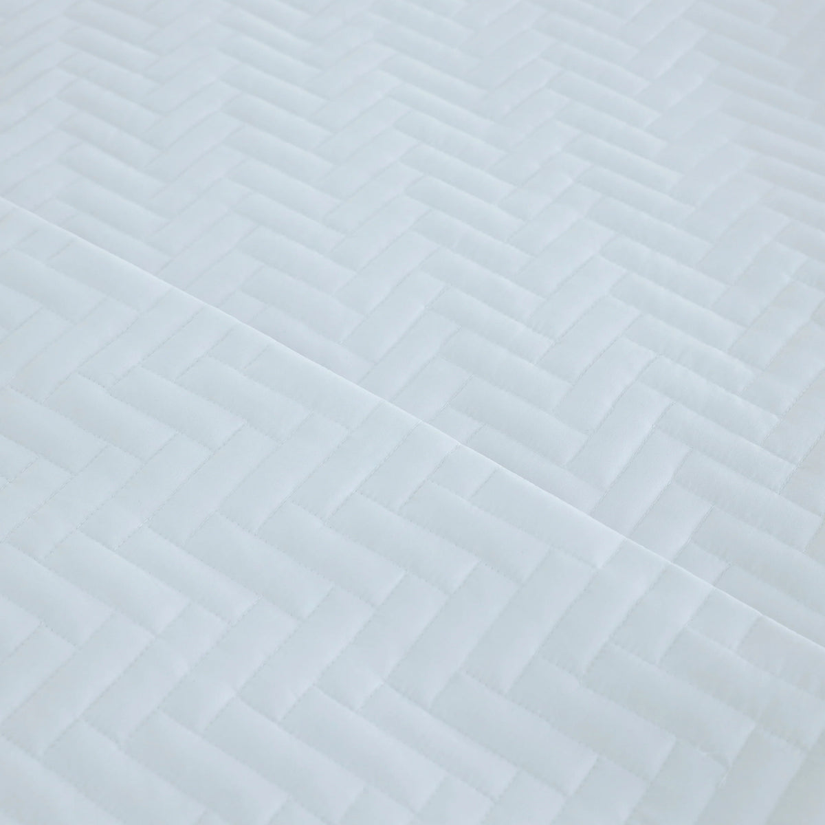 Pictured: Ultra closeup of the white Martex Suites Coverlet. You can see the herringbone pattern and the texture of the coverlet.