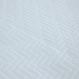 Pictured: Ultra closeup of the white Martex Suites Coverlet. You can see the herringbone pattern and the texture of the coverlet.