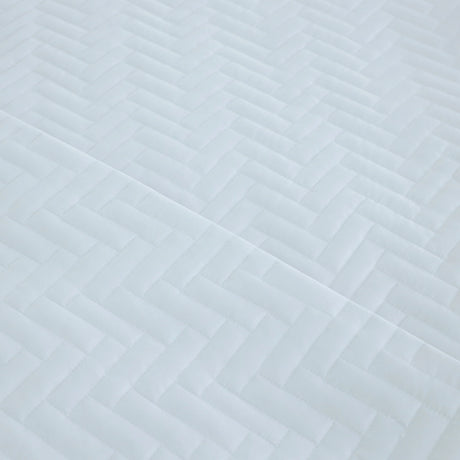 Pictured: Ultra closeup of the white Martex Suites Coverlet. You can see the herringbone pattern and the texture of the coverlet.