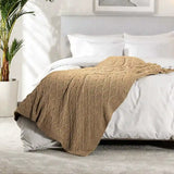 Beige knitted blanket on a bed in a bedroom setting