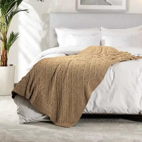 Beige knitted blanket on a bed in a bedroom setting