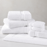 Set of white towels stacked on a light gray surface with a neutral background
