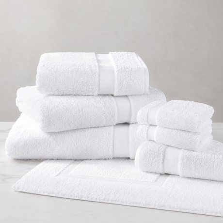 Set of white towels stacked on a light gray surface with a neutral background