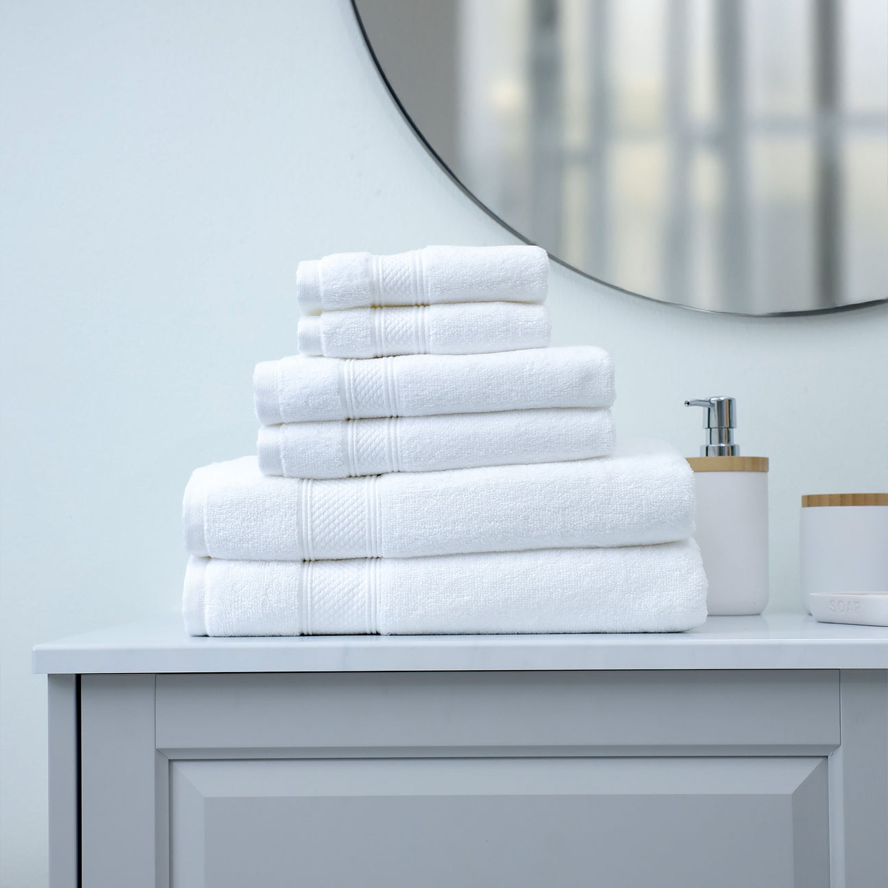 Stack of white towels on a bathroom counter with a mirror in the background