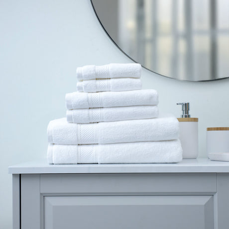 Stack of white towels on a bathroom counter with a mirror in the background
