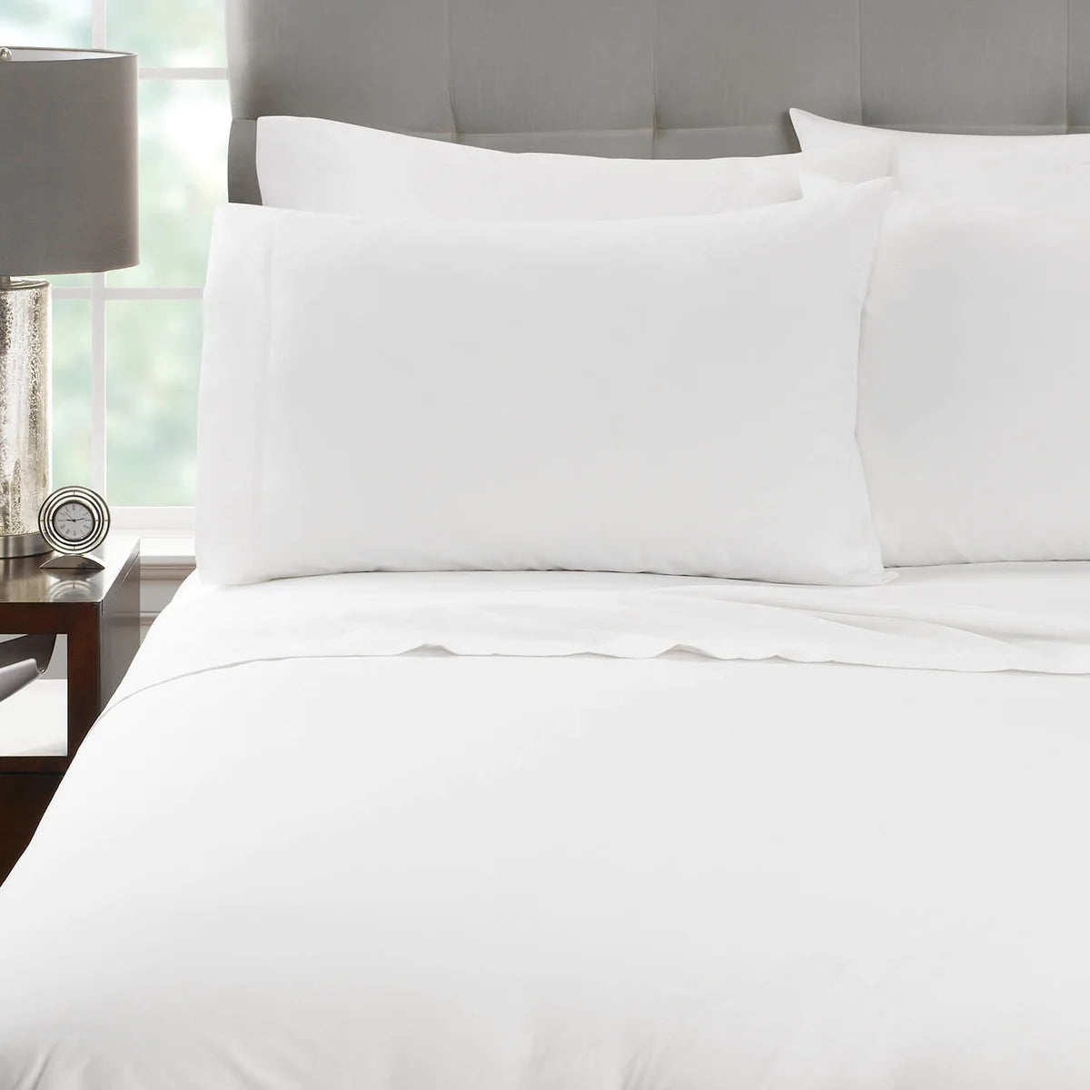 Pictured: Nicely made white bed on a grey fabric bedframe. The bedding features the Millennium T-250 Sheets.