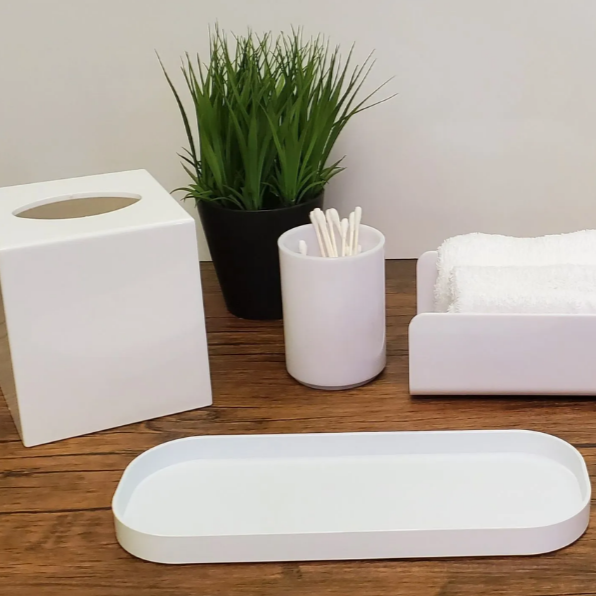 White bathroom accessories including a tissue box, tray, and soap dish on a wooden surface.
