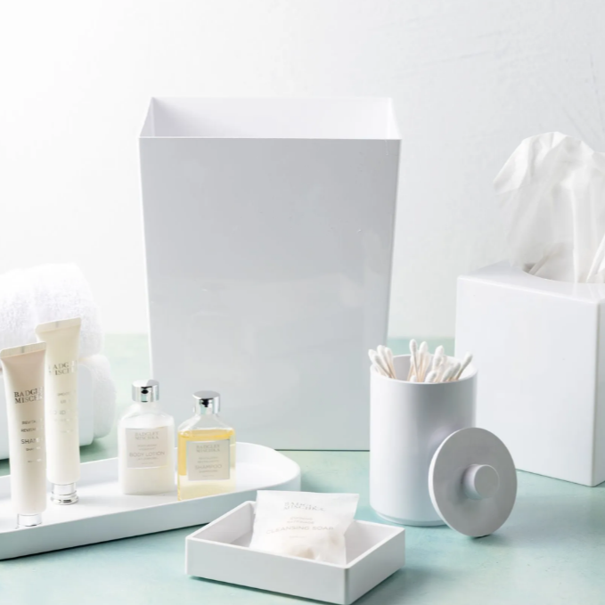 White bathroom accessories including a towel, soap, and toothbrush holder on a light blue surface.