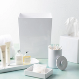White bathroom accessories including a towel, soap, and toothbrush holder on a light blue surface.