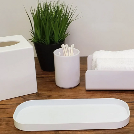 White bathroom accessories including a tissue box, tray, and soap dish on a wooden surface.