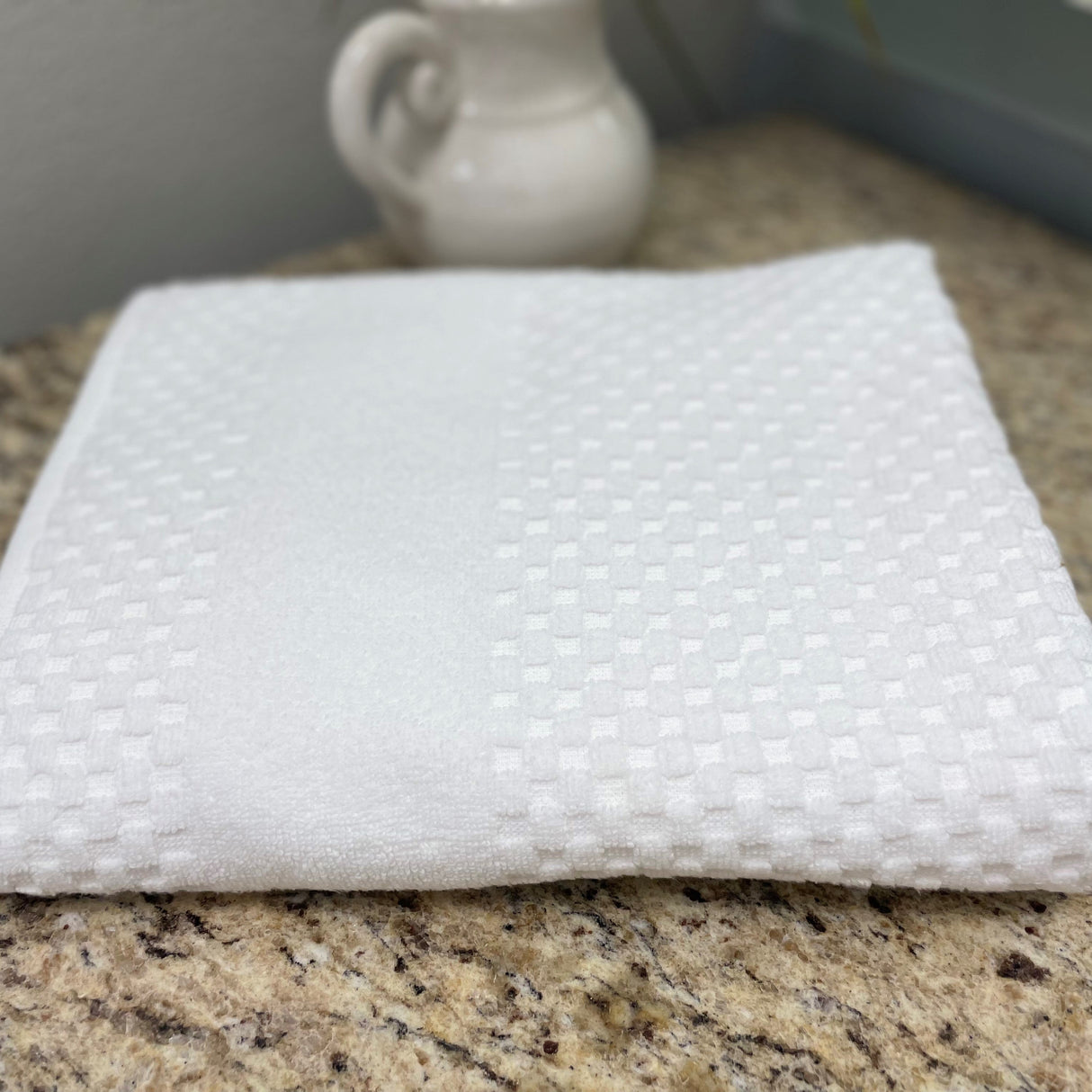 White textured cloth on a granite countertop with a blurred background