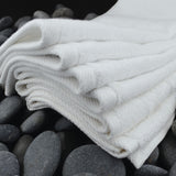 Stack of white folded towels on dark gray stones