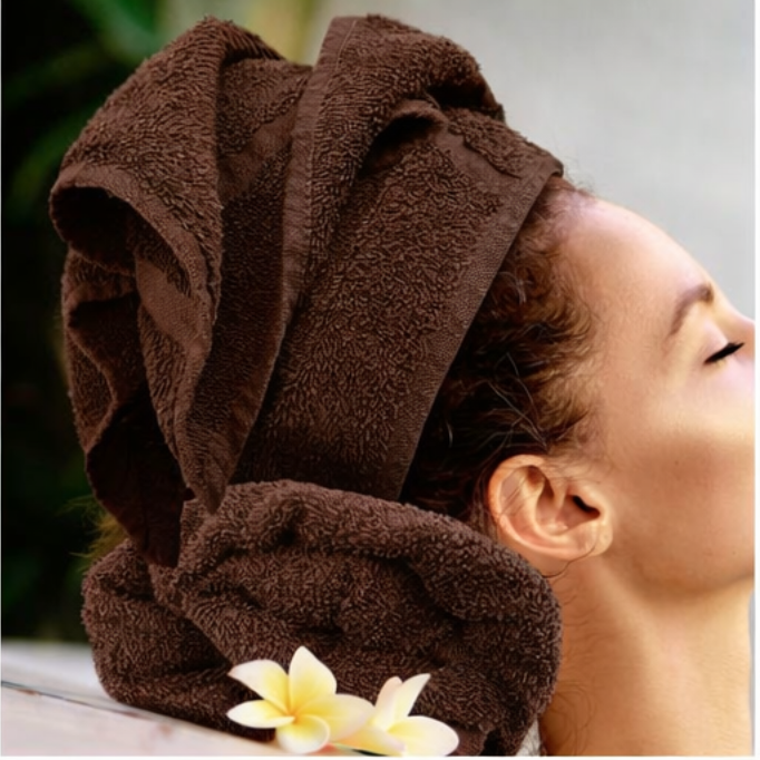 Person with a brown towel wrapped around their head, with flowers on a blurred background