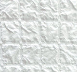 White textured fabric with a stitched grid pattern of square panels.