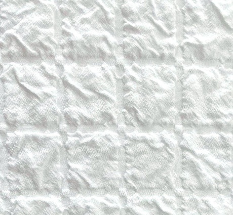 White textured fabric with a stitched grid pattern of square panels.