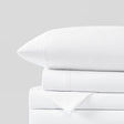 Stacked white bed sheets and pillowcase on a gray background