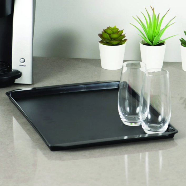 Black tray on a kitchen counter with glasses and potted plants.